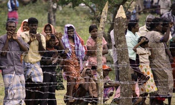 Civilians stand behind the barbed-wire perimeter fence of the Manik Farm refugee camp near Vavuniya, Sri Lanka. Photograph: David Gray -Reuters-REUTERS