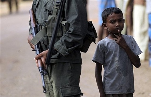 A young Sri Lankan refugee displaced during the final stages of the fighting, stands beside a soldier