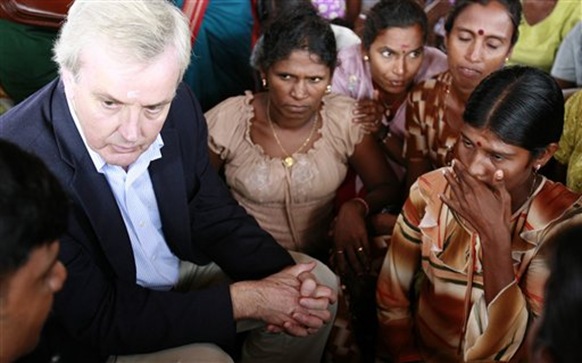 In this photo provided by the United Nations, U.N. Undersecretary-General for Humanitarian Affairs John Holmes, left, speaks with a group of resettled internally displaced people at a camp for the displaced in Vavuniya, Sri Lanka, Wednesday, Nov. 18, 2009. Holmes visited northern Sri Lanka to study the welfare of war-displaced civilians held in camps and those recently resettled. (AP Photo/United Nations)