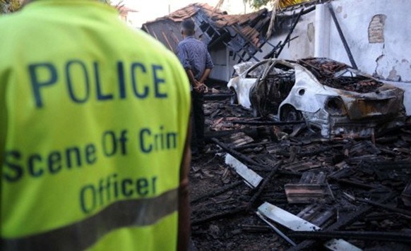 Sri Lankan police check the wreckage of the home of an opposition activist following a bomb attack