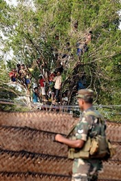 Sri Lankan military stand guard as war-displaced civilians look on at a state-run internment camp in Vavuniya in 2009