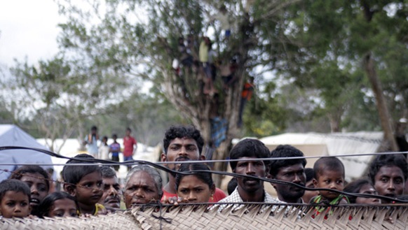 Displaced Sri Lankan Tamils gaze past a fence at an internment camp in Vavuniya in November 2009. (Reuters)