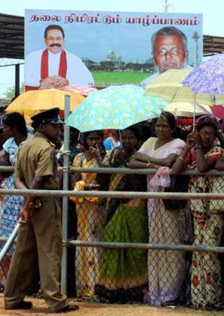 Sri Lankan policeman watches over a crowd of political supporters as President Mahinda Rajapaksa attends a rally in Jaffna on April 1, 2010 afp
