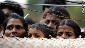 Sri Lankan war-displaced civilians peer from behind barbed wire fences surrounding their internment camp in Vavuniya