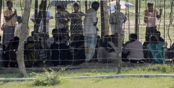 Ethnic minority Sri Lankan Tamil civilians peer from behind a barbedwire fence around a camp for displaced people