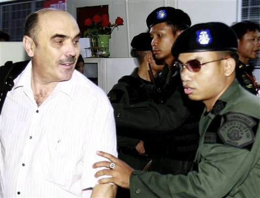 An unidentified detained crew member of a seized plane carrying 35 tons of weapons from North Korea, left, is escorted to criminal court to seek court detention in Bangkok, Thailand Monday, Dec. 14, 2009. The crew of a cargo plane loaded with war weapons from North Korea was ordered Monday to remain in a Thai prison for 12 days for further investigations. Members of the five-man crew, four from Kazakhstan and one from Belarus, were charged Sunday with illegal arms possession and refused bail. (AP Photo/Apichart Weerawong)