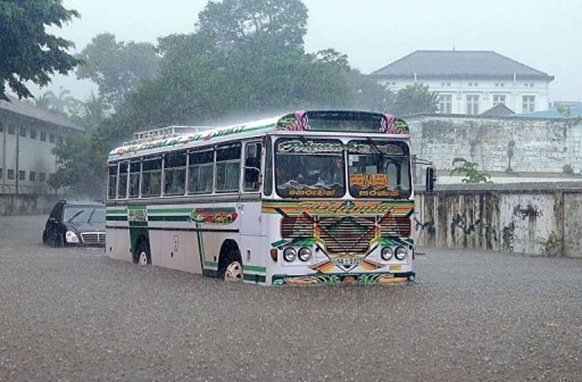 Vehicles drive along a flooded road in Colombo