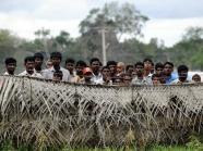 Displaced Sri Lankan civilians look out from behind barbed wire fences surrounding their internment camp in Vavuniya afp