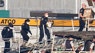 Members of the Canada Border Services Agency are seen wearing surgical masks as they board the MV Sun Sea. (Jonathan Hayward-Canadian Press)