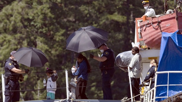 Tamil migrants, including some children, are escorted from the MV Sun Sea after it arrived at CFB Esquimalt on Friday.  (Jonathan Hayward-Canadian Press)