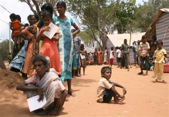 Tamil civilians stand next to their huts in a refugee camp located on the outskirts of the town of Vavuniya in northern Sri Lanka May 6, 2009. REUTERS-Stringer