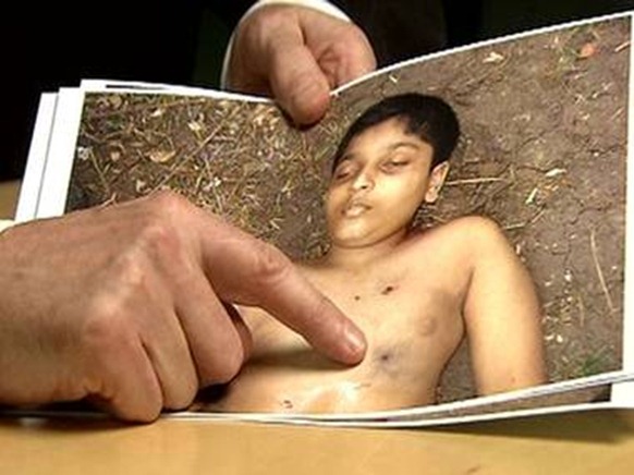 Derrick Pounder points out one of the five bulletwounds in the body of Balachandran Prabhakaran, 12, in Channel 4's Killing Fields Channel 4