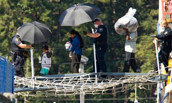 A family is escorted off the MV Sun Sea on Vancouver Island in 2010. Photograph: Andy Clark/Reuters