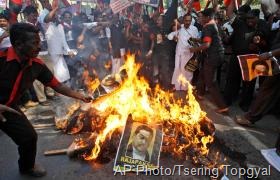 Indian Tamil activists of the Marumalarchi Dravida Munnetra Kazhagam (MDMK) party burn an effigy and portraits of Sri Lankan President Mahinda Rajapaksa during a protest in New Delhi, India, Friday, Feb. 8, 2013. Various pro-Tamil groups and leaders are protesting Rajapaksa’s visit holding him responsible for the killing of innocent Tamils during the civil war in Sri Lanka. Rajapaksa is on a personal visit to the country. (AP Photo/Tsering Topgyal)