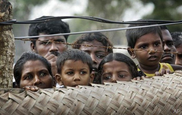 Internally displaced Sri Lankan Tamil civilians peep from over a fence at a camp for the displaced in Vavuniya, Sri Lanka. File photo 